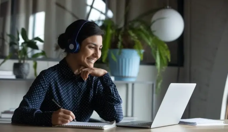 Happy young indian girl with headphones looking at laptop screen picture id1216915208