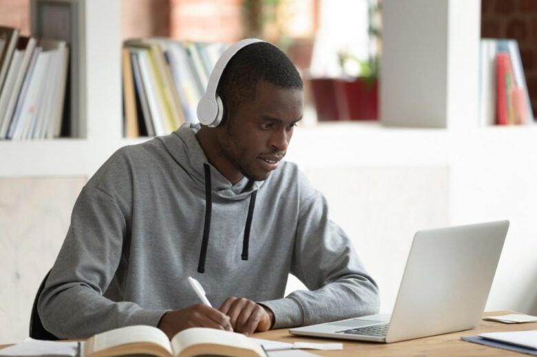 African guy elearning seated at desk in public library picture id1187643127