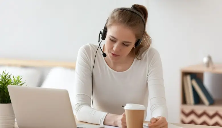 Focused woman in headset using laptop writing notes picture id1143696570
