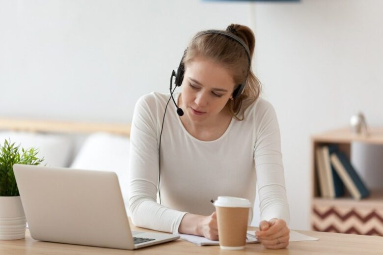 Focused woman in headset using laptop writing notes picture id1143696570