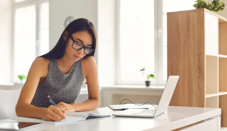 Student in glasses taking notes while watching webinar or listening picture